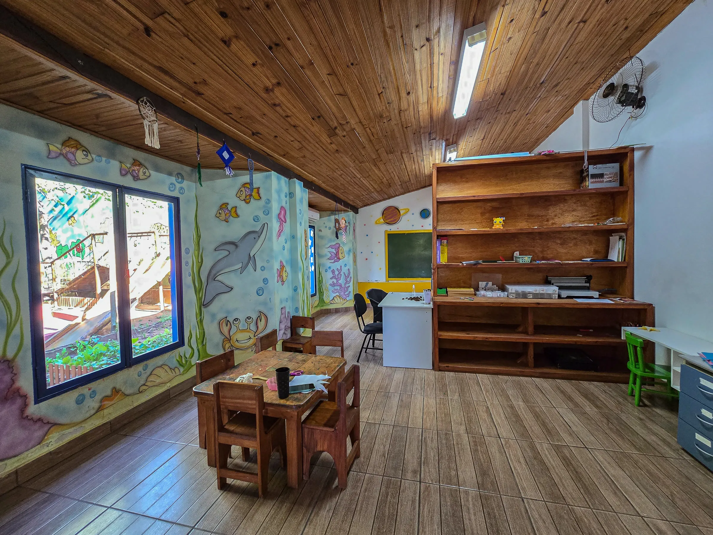 Sala de atividades com mesas e estantes
