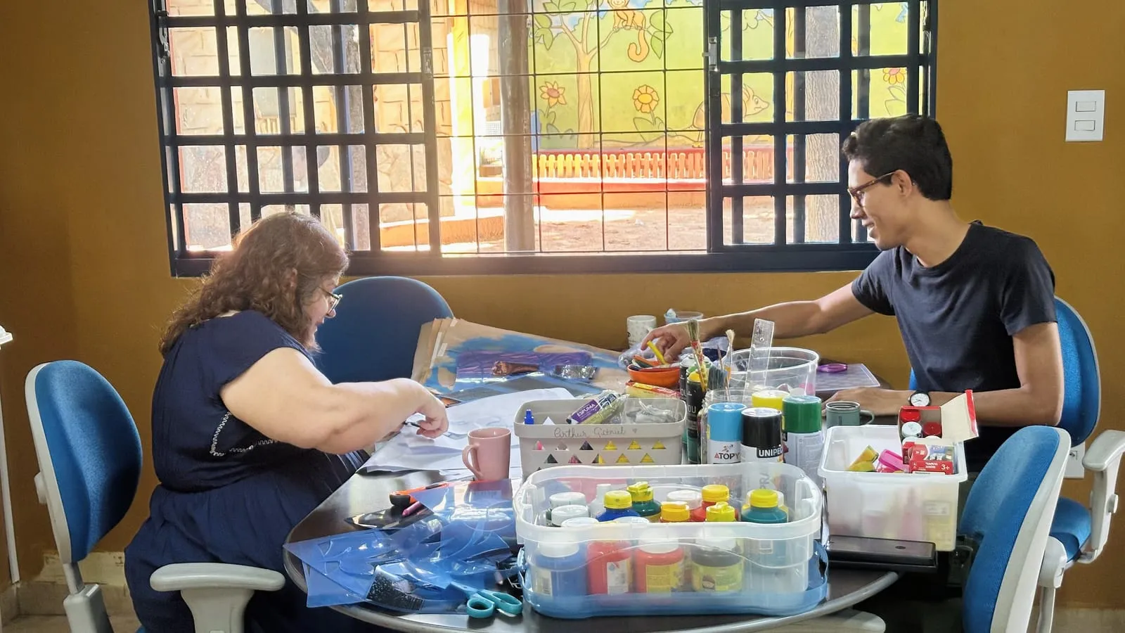 Mulher organizando tintas e materiais em uma mesa