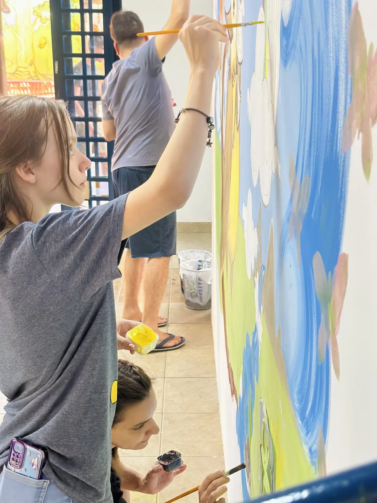 Participante pintando o mural com pincel fino